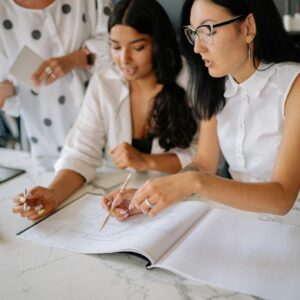 Professional women discussing project details during a collaborative office meeting.